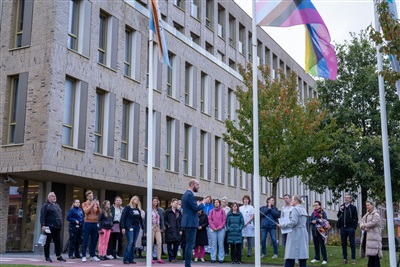 Vele genodigden keken toe tijdens het hijsen van de regenboogvlag